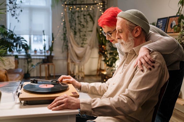 Loving couple sharing a moment listening to vinyl records in a cozy home setting.